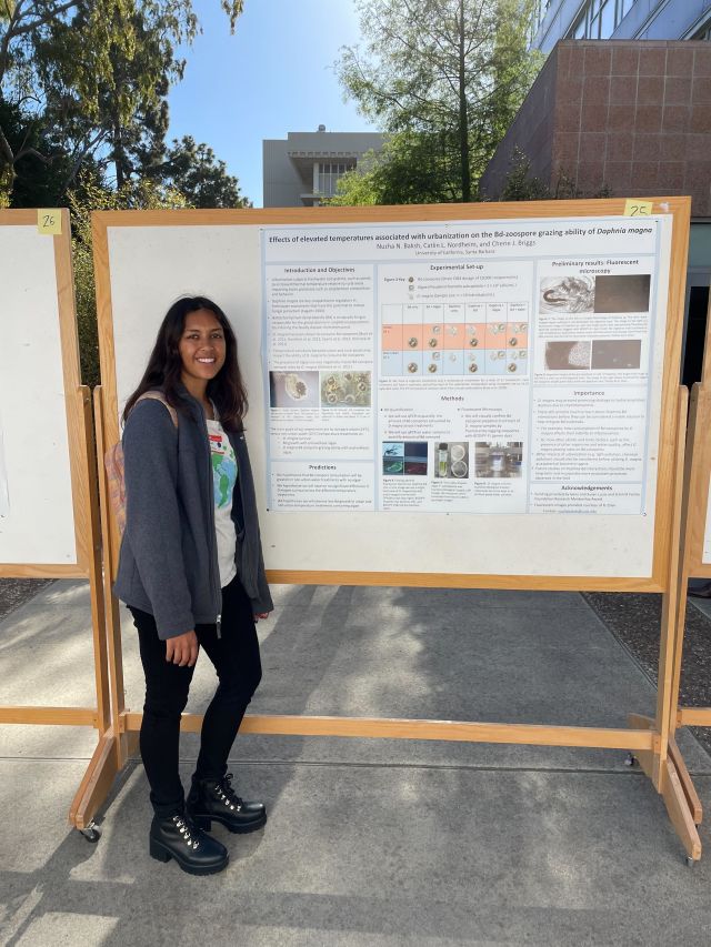Photo of Nuzha standing next to their poster